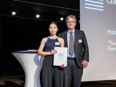 Yixin Chen and Jan-Michael Rost posing on stage during the graduation ceremony, with Yixin holding a certificate.