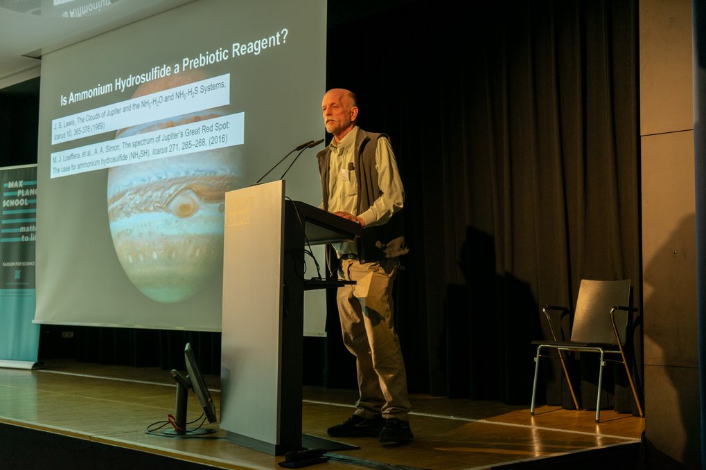 Nicholas Hud giving a lecture with a Jupiter image on the screen.