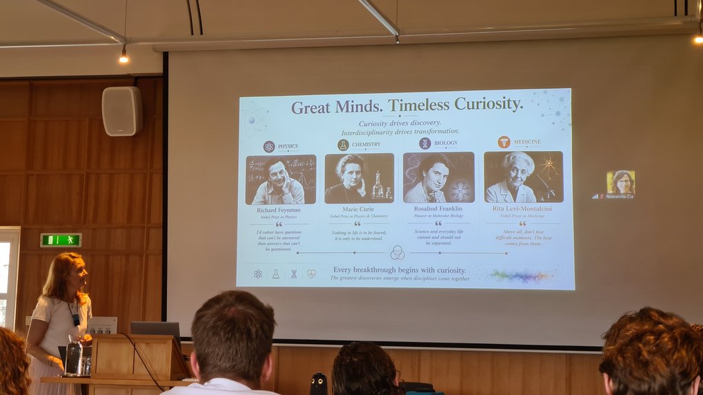 Slide titled "Great Minds. Timeless Curiosity." featuring portraits and quotes from Richard Feynman, Marie Curie, Rosalind Franklin, and Rita Levi-Montalcini in a lecture setting.