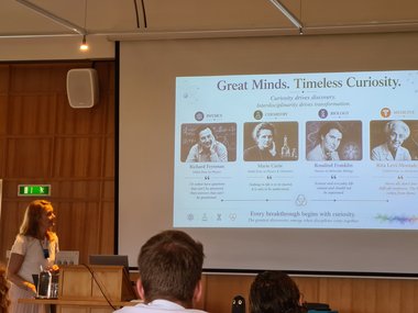 Slide titled "Great Minds. Timeless Curiosity." featuring portraits and quotes from Richard Feynman, Marie Curie, Rosalind Franklin, and Rita Levi-Montalcini in a lecture setting.