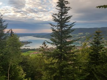 The view from Ringberg Castle is incredible View of lake Tegernsee over high trees under a slightly orange colored sky